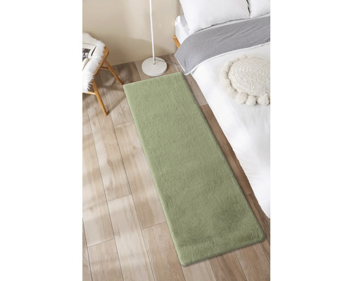 Grüner Teppich neben einem Bett auf einem Holzboden