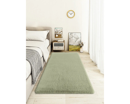 Schlafzimmer mit Bett, Nachttisch, Wanduhr und rechteckigem Teppich