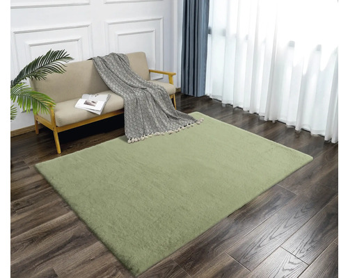 Wohnzimmer mit Sofa und grünem Teppich auf Holzboden