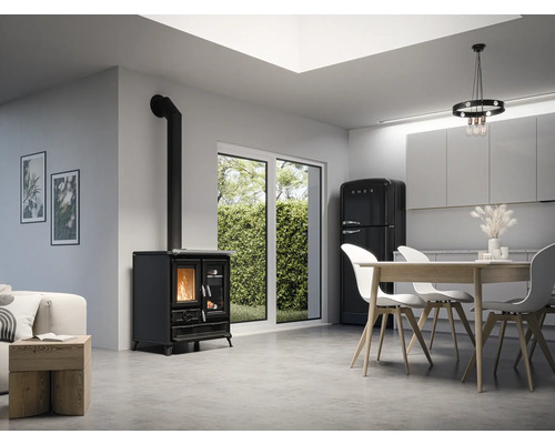 Wohnraum mit Holzofen, Esstisch, Stühlen und Kühlschrank.