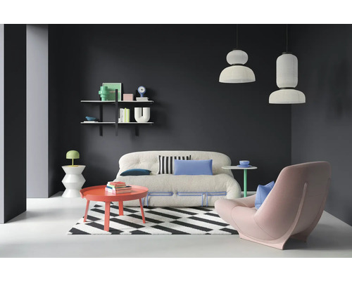 Wohnzimmer mit Sofa, Sessel, Teppich, Tisch und Wandregal.