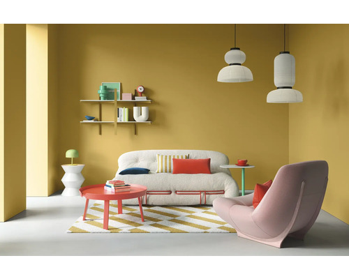 Wohnzimmer mit Sofa, Sessel, Tisch, Regalen und Pendelleuchten vor gelber Wand