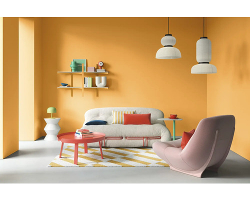 Wohnzimmer mit Sofa, Sessel, Teppich und Dekoration vor orangefarbener Wand