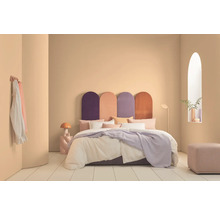 Schlafzimmer mit Bett, farbigem Kopfteil, Nachttischlampe und Dekoration