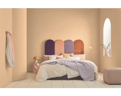 Schlafzimmer mit Bett, farbigem Kopfteil, Nachttischlampe und Dekoration