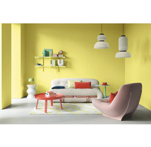 Wohnzimmer mit Sofa, Sessel, Couchtisch, Regalen und Pendelleuchten vor gelber Wand