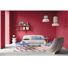 Wohnzimmer mit Sofa, Sessel, Teppich, Tisch und Regalen vor roter Wand