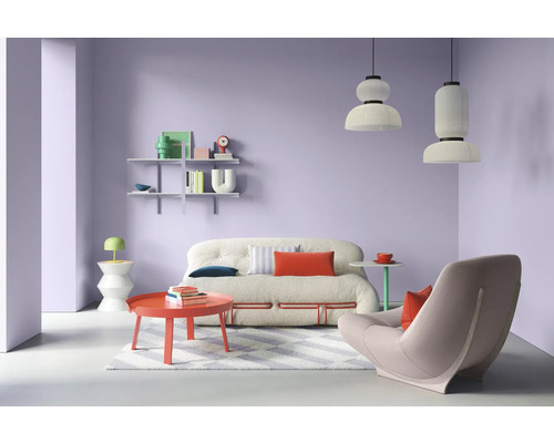 Wohnzimmer mit Sofa, Sessel, Tisch und Regalen vor lila Wand