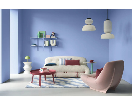 Wohnzimmer mit Sofa, Sessel, Couchtisch, Regalen und Pendelleuchten in einem hellen Raum