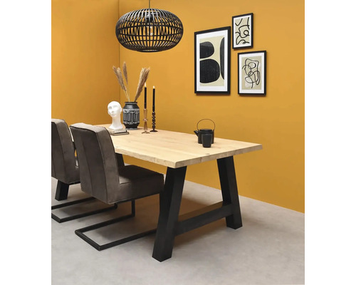 Moderner Essbereich mit Massivholztisch, schwarzen Metallbeinen, grauen Polsterstühlen und schwarzer Käfig-Pendelleuchte vor gelber Wand.
