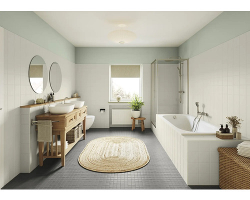 Badezimmer mit Waschtisch, Spiegeln, Badewanne und geflochtenem Teppich