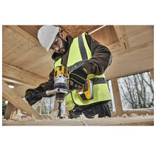 Ein Bauarbeiter bohrt mit einer gelben DeWalt Bohrmaschine in ein Holzstück.