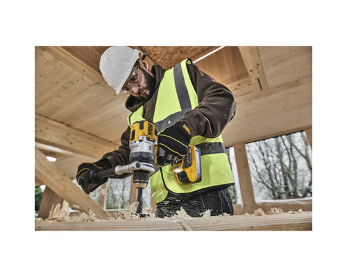 Ein Bauarbeiter bohrt mit einer gelben DeWalt Bohrmaschine in ein Holzstück.