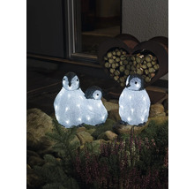 Drei leuchtende Pinguinfiguren als Dekoration im Garten.