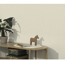 Wohnraum mit einer strukturierten Tapete, dekoriert mit einer Pflanze, einer Pferdefigur und Büchern auf einem Tisch