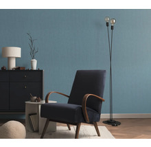 Wohnzimmer mit Sessel, Stehlampe und Kommode vor einer blauen Wand