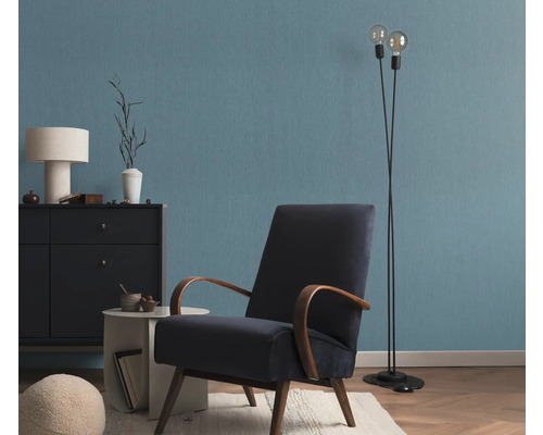 Wohnzimmer mit Sessel, Stehlampe und Kommode vor einer blauen Wand