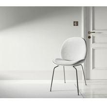 Szene mit einem Stuhl mit Metallbeinen und gepolstertem Sitz in einem hellen Raum.