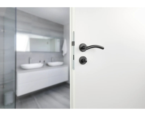 Geöffnete weiße Tür mit schwarzer Türklinke vor Badezimmer