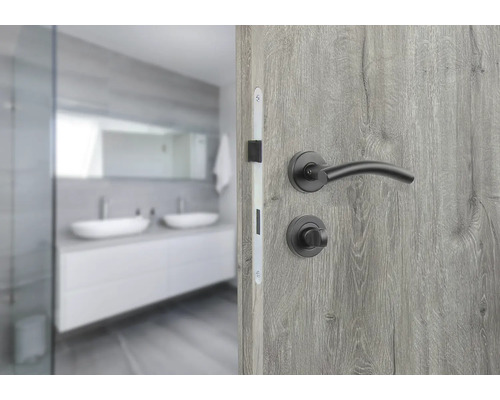 Teilansicht eines Badezimmers mit Tür und schwarzem Türdrücker