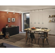 Esszimmer mit Holztisch, schwarzen Stühlen, Kommode und Beleuchtungssystem