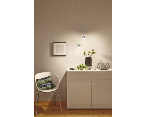 Helles Interieur mit Sideboard, Sessel und Pendelleuchten für eine freundliche Atmosphäre.