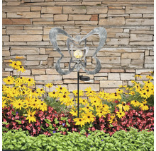 Dekorative Gartenleuchte mit Schmetterlingsmotiv und Solarpanel zwischen Blumenbeet