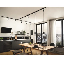 Moderne Küche mit linearem Schienensystem und Pendelleuchten über einem Holztisch.