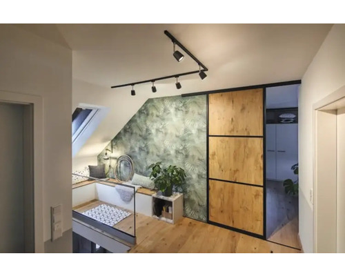 Helle Dachgeschosswohnung mit Dachfenster, Sitzecke, grüner Blättertapete, Schiebetür und Holzfußboden.