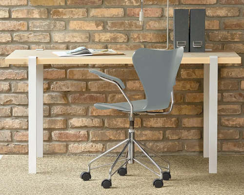 Schreibtisch mit Bürostuhl vor einer Ziegelwand