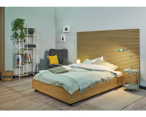 Schlafzimmer mit Bett, Nachttisch, Lampe, Sessel und Bücherregal