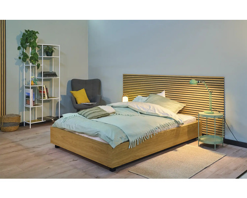 Schlafzimmer mit Bett, Nachttisch, Lampe, Regal und Sessel für eine wohnliche Atmosphäre