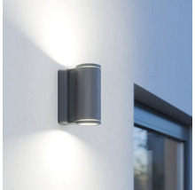 Graue LED-Außenwandleuchte mit zylindrischem Design an einer Wand