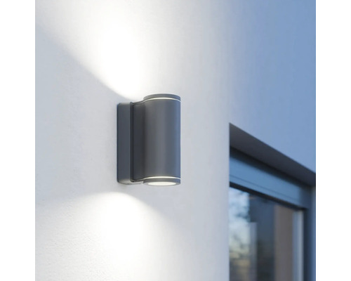 Graue LED-Außenwandleuchte mit zylindrischem Design an einer Wand