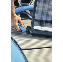 Person schließt einen blauen Schlauch an einen Solarabsorber an.