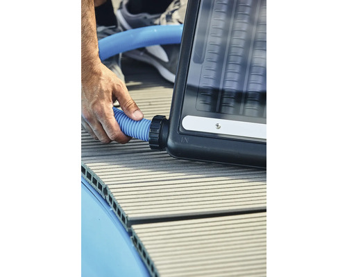 Person schließt einen blauen Schlauch an einen Solarabsorber an.