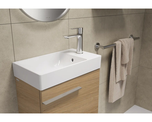 Waschtisch mit Armatur, Handtuch und Spiegel im Badezimmer
