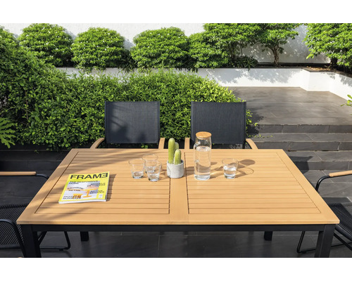 Gartenszene mit Esstisch, Stühlen, Gläsern, Wasserkaraffe, Zeitschrift und Kaktus