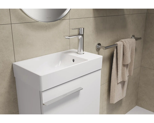 Badezimmerwaschtisch mit Armatur, Handtuchhalter und Handtuch.