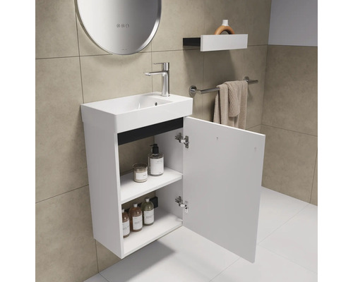 Badezimmer mit Waschbeckenunterschrank, Waschbecken und geöffneter Schranktür