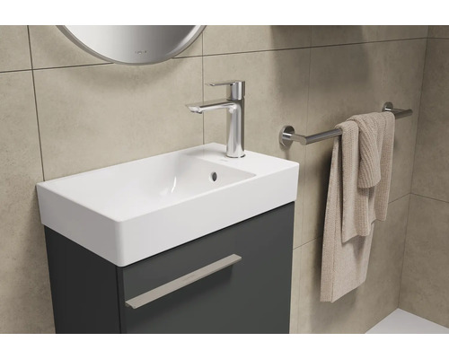 Badezimmer Waschbecken mit Unterschrank, Armatur und Handtuchhalter an der Wand