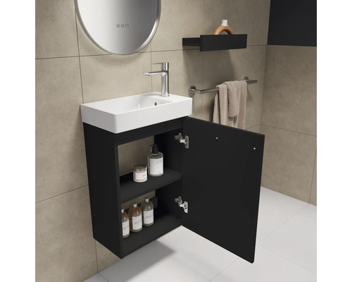 Badezimmer mit Waschbecken, Unterschrank und geöffneter Tür zur Aufbewahrung von Badutensilien
