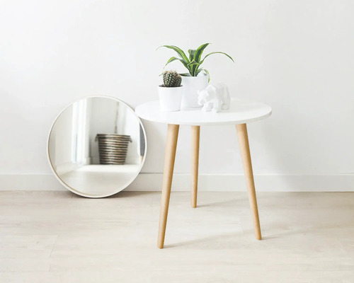 Dekorative Szene mit einem Spiegel, einem Tisch mit Pflanzen und einer Bärenfigur.