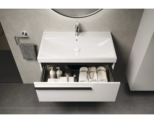 Waschtisch mit offenem Schubfach, Handtüchern und Pflegeprodukten im Badezimmer.