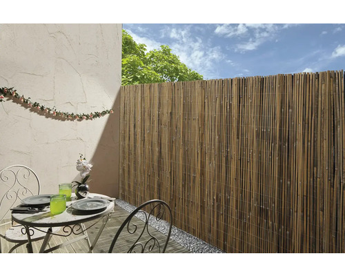 Außenbereich mit Bambuszaun, Tisch und Stühlen