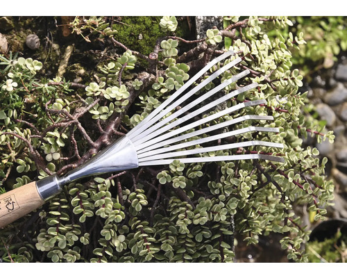 Fächerbesen aus Metall mit Holzgriff vor Grünpflanzen