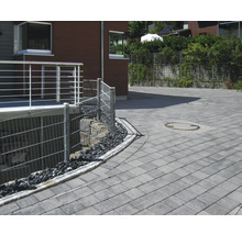 Außenansicht mit Pflastersteinen, Zäunen und Bepflanzung