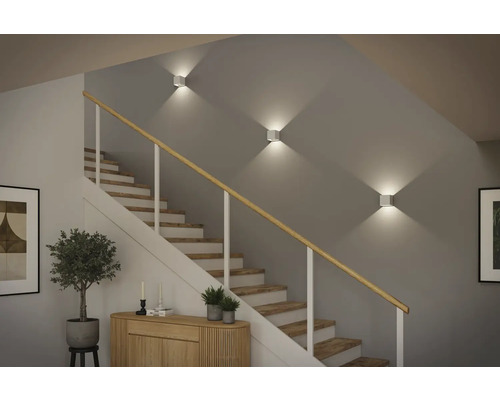 Treppenhaus mit Treppe, Treppengeländer und drei quadratischen Wandleuchten