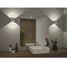 Helles Badezimmer mit Spiegel, Waschbecken und zwei Wandleuchten