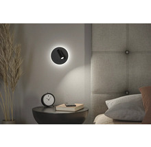 Schlafzimmer-Szene mit einem runden LED-Wandspot über einem Nachttisch mit Dekoration